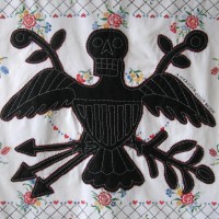 From the series American Memento Mori: Eagle - applique and embroidery on vintage textile. A folk art figure of an eagle in silhouette with a skeleton head is appliquéd onto a colorful vintage tablecloth, and embellished with white embroidery.